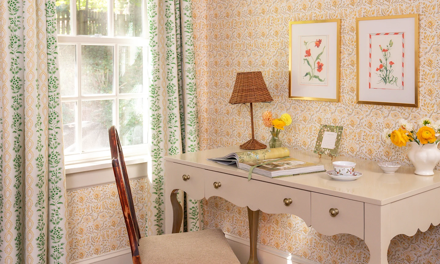Yellow floral wallpaper and coordinating curtain in a guest bedroom with a desk.