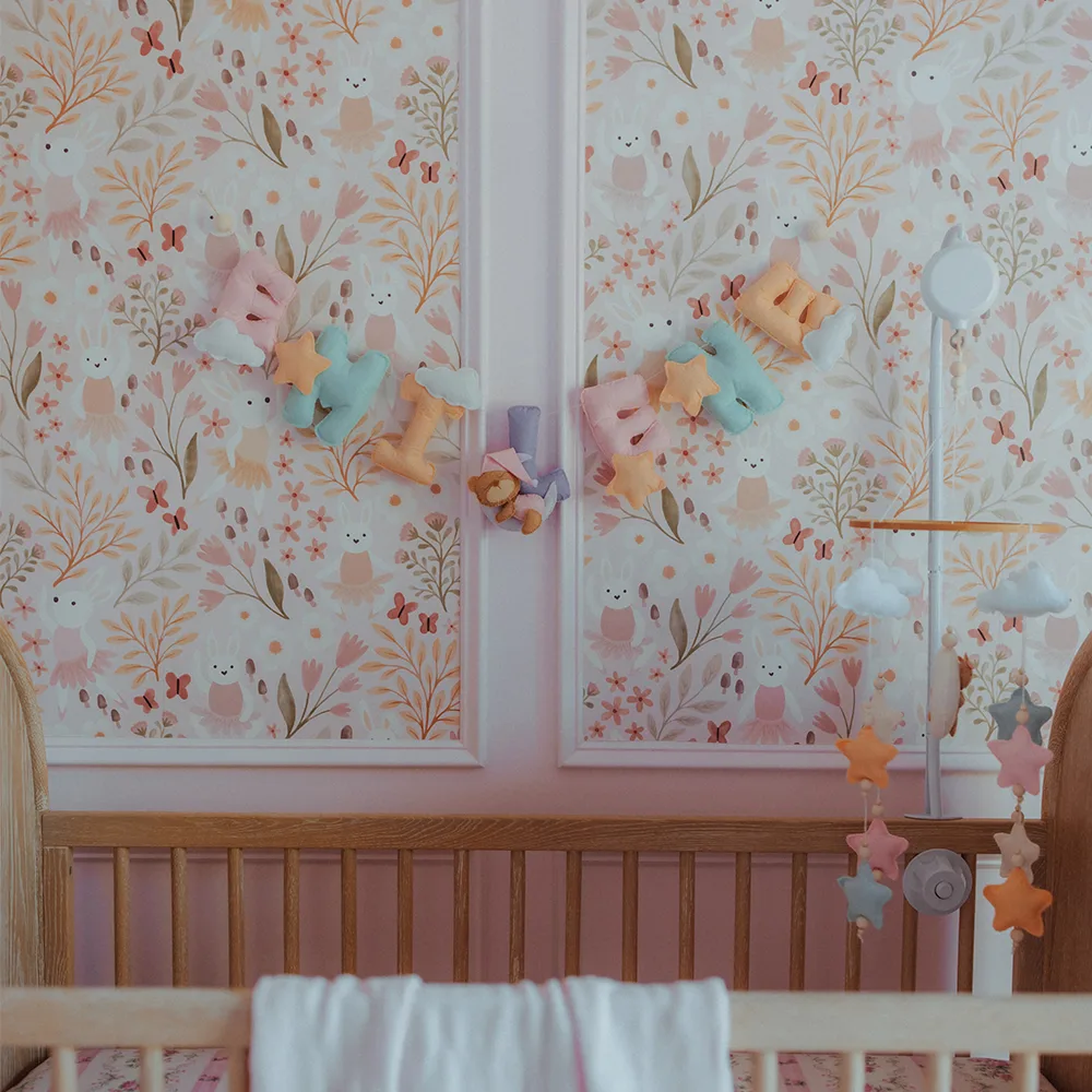 Nursery with pink floral wallpaper above the crib.