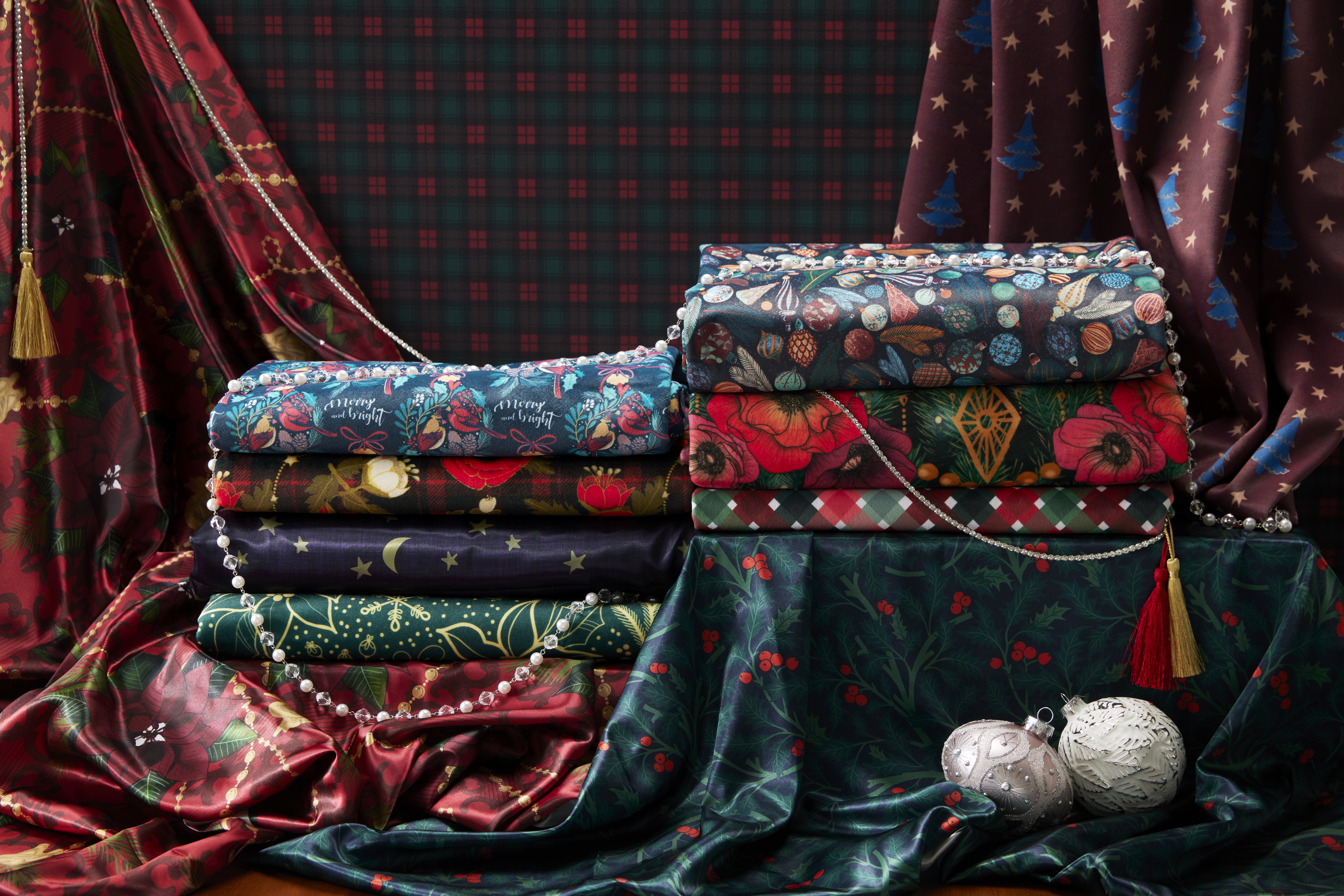 A luxurious stack of satin and velvet fabrics with dark and saturated holiday prints