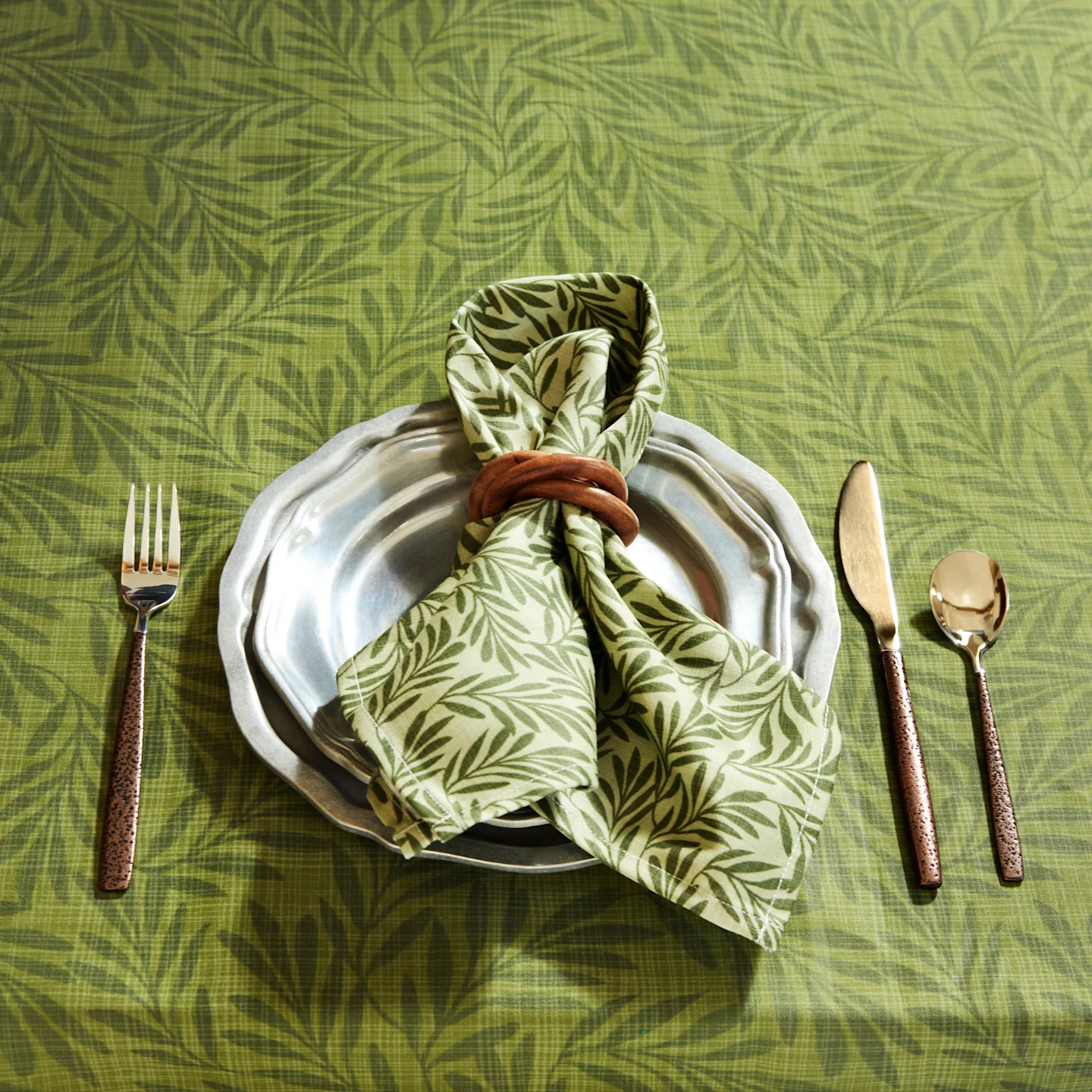 Dining table with a place setting with a green dinner napkin and placemat.