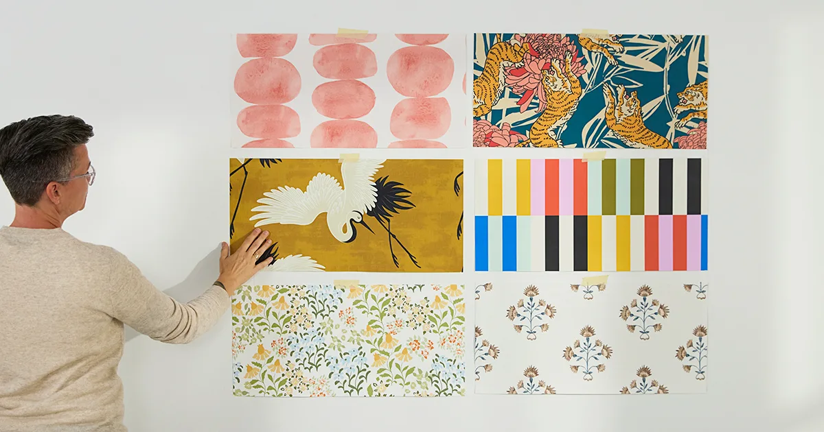 Person assessing 6 wallpaper samples on a wall.