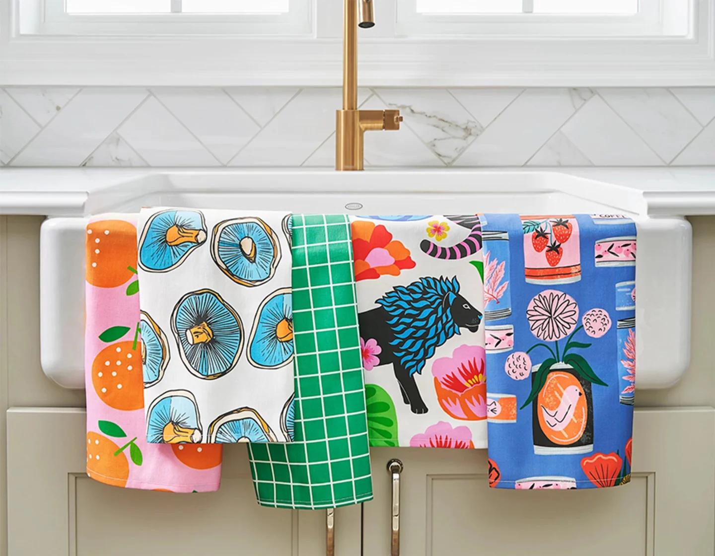 Multiple colorful tea towels hanging on kitchen sink.