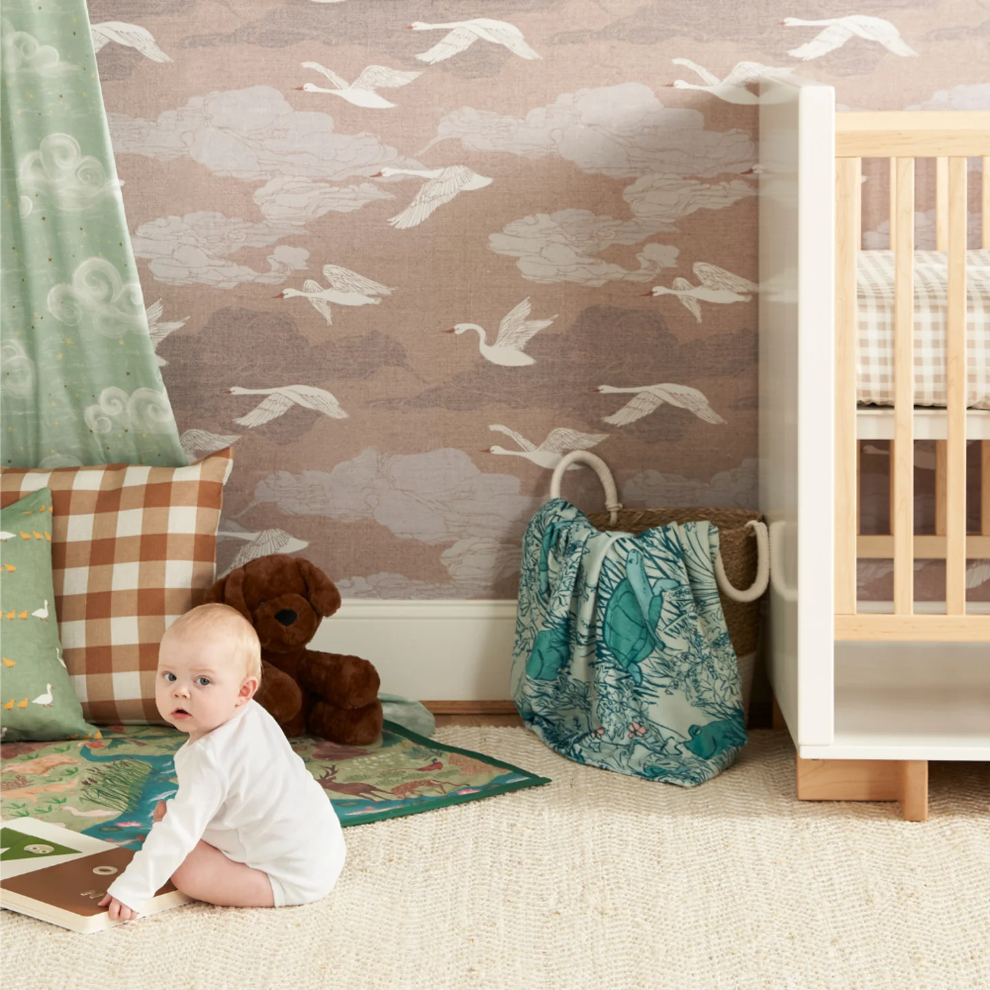 Baby playing in a nursery with swan wallpaper